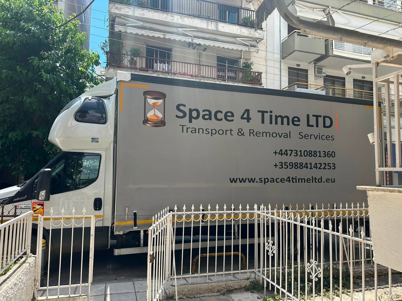 Removal truck and furniture lift working on a narrow street